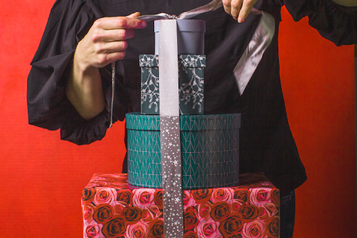 Stack of gift boxes being unwrapped with ribbon.