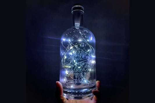 Hand-engraved glass bottle with LED lights and personalized design.