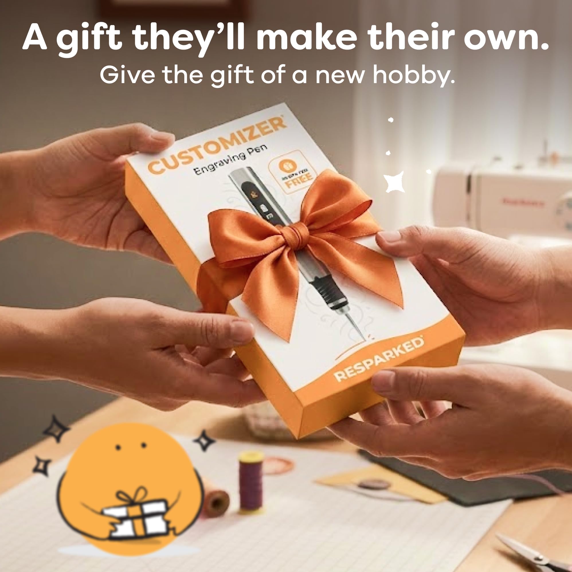 Box of a customizer pen with an orange bow, held by two hands with sewing machine in background.